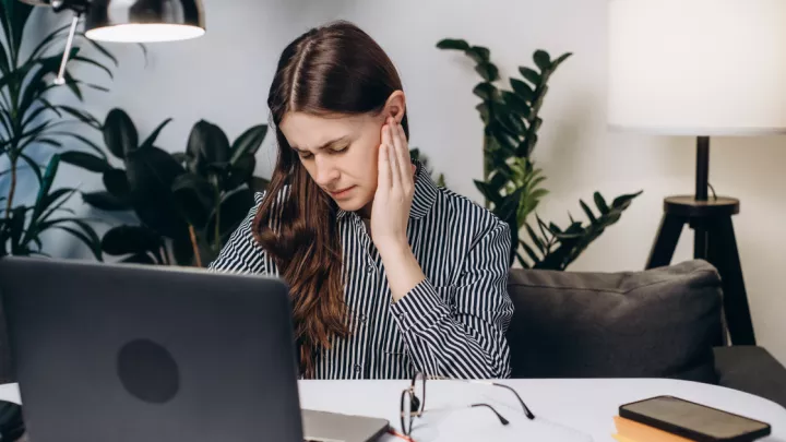 A picture of a woman holding her ear in pain