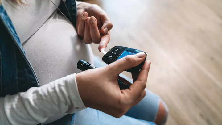 Pregnant woman using glucose meter