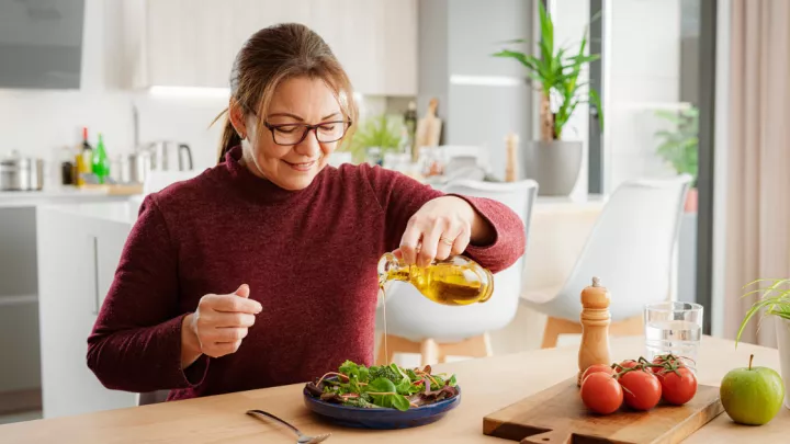 Woman pouring oil on salad