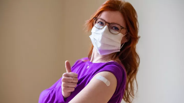 Masked woman showing off bandaid