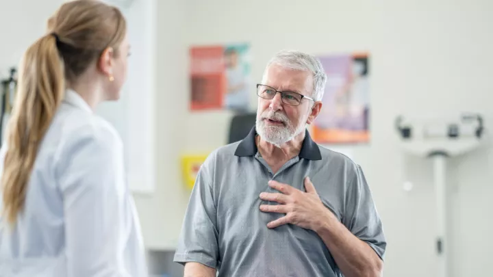 Man touching his chest and talking to doctor