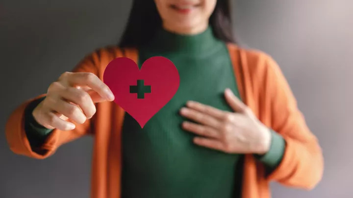 Woman holding paper cut out of a heart