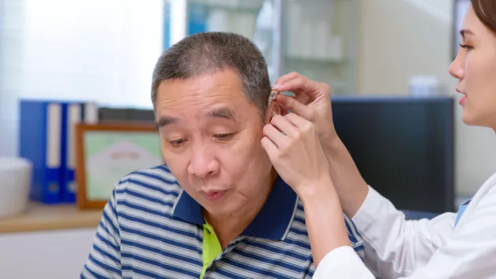 Older man getting his hearing aid adjusted by a doctor