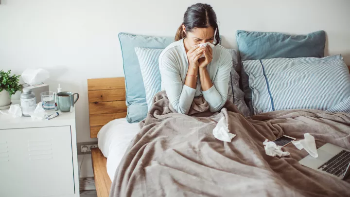 Woman blowing her nose in bed