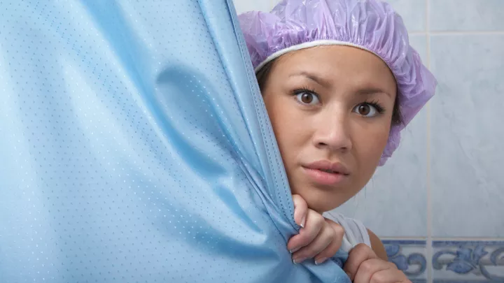 Woman peeking out from shower curtain